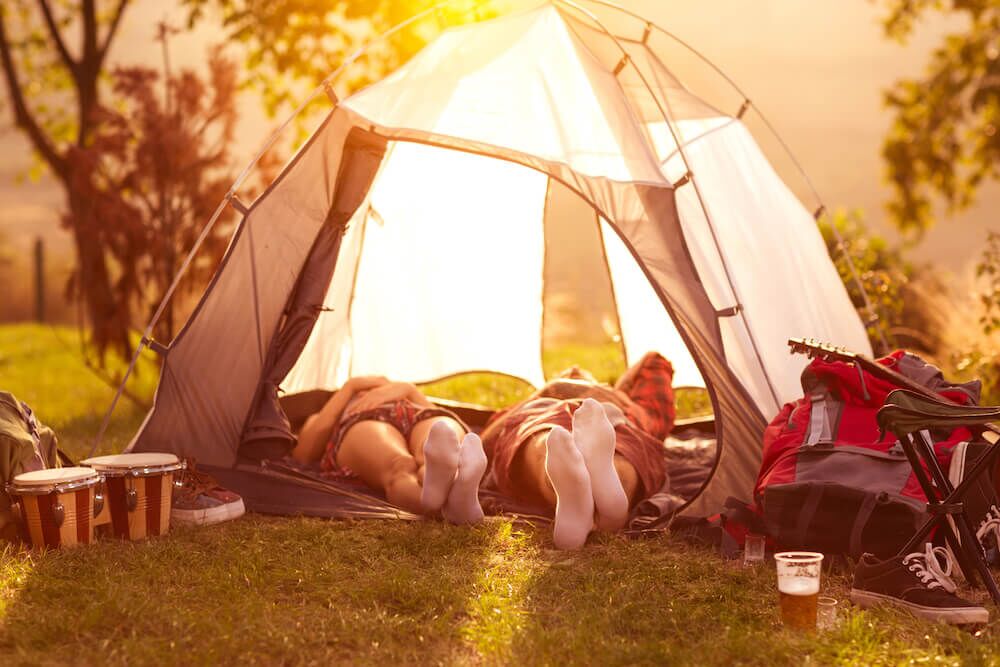 summer music festival tent camping, two people laying in tent with sunset